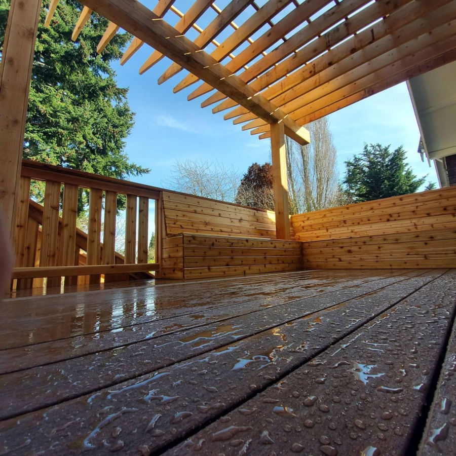 Composite decking boards up close, matching cedar pergola and bench in sight