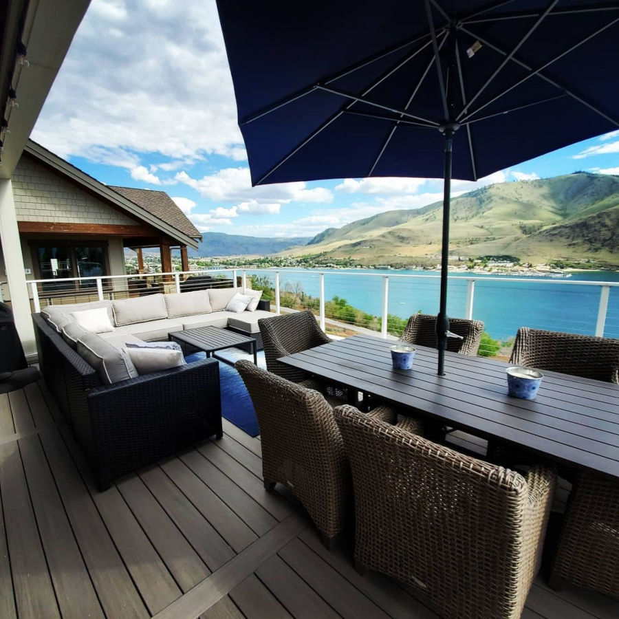 Deck furniture couch and table on balcony overlooking lake.