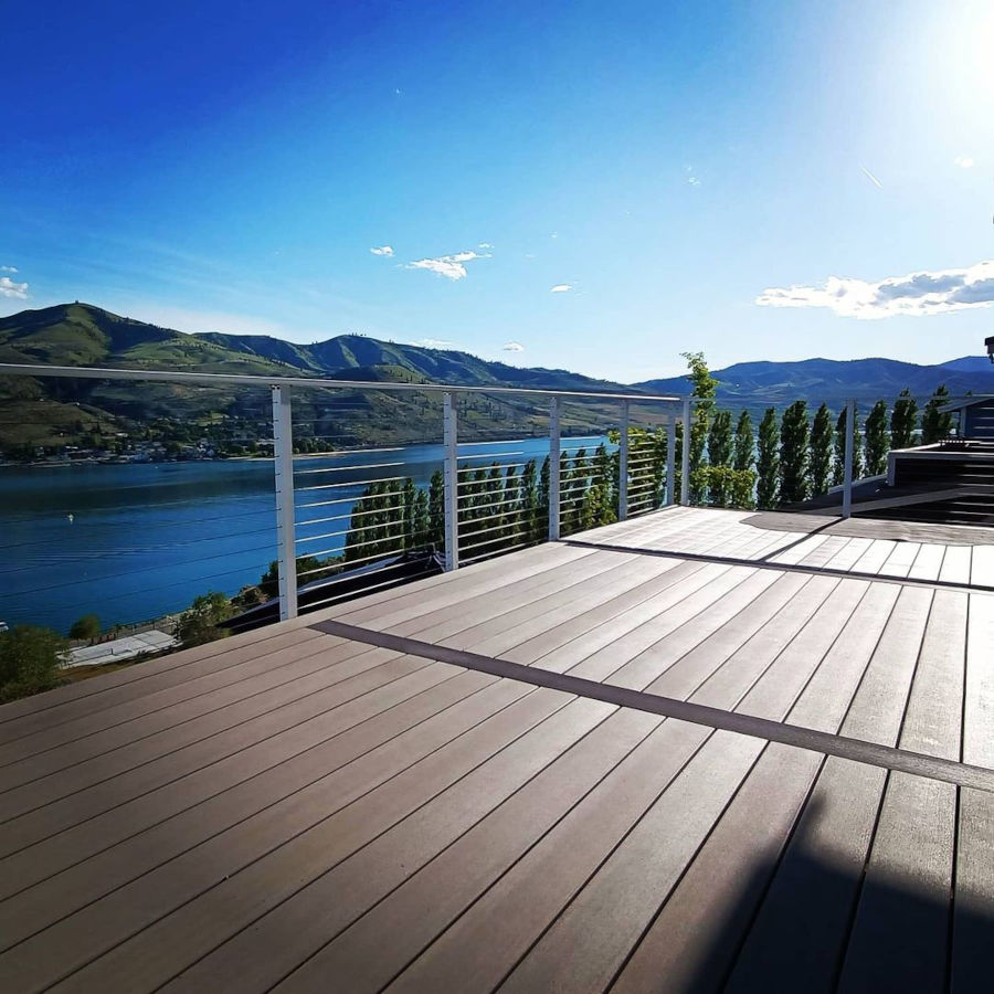 Deck overlooking lake water light tan dark accents with white cable railing.