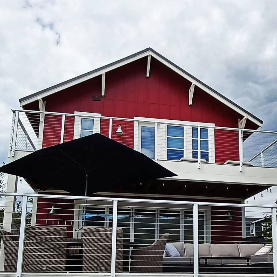 Red white house with cable railing on deck balcony.