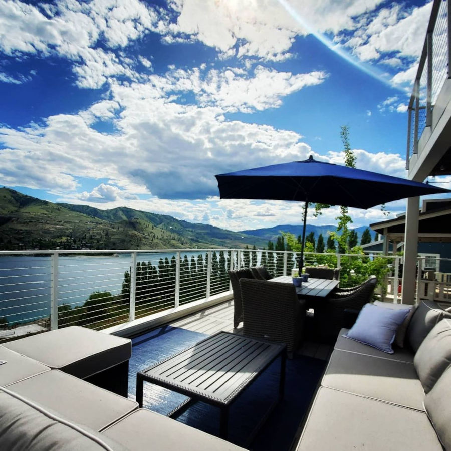 Deck overlooking lakefront view with complimentary furniture white cable railing.