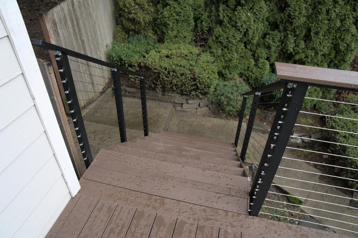 Redmond deck build looking down balcony stairs steel cable handrail green hedges