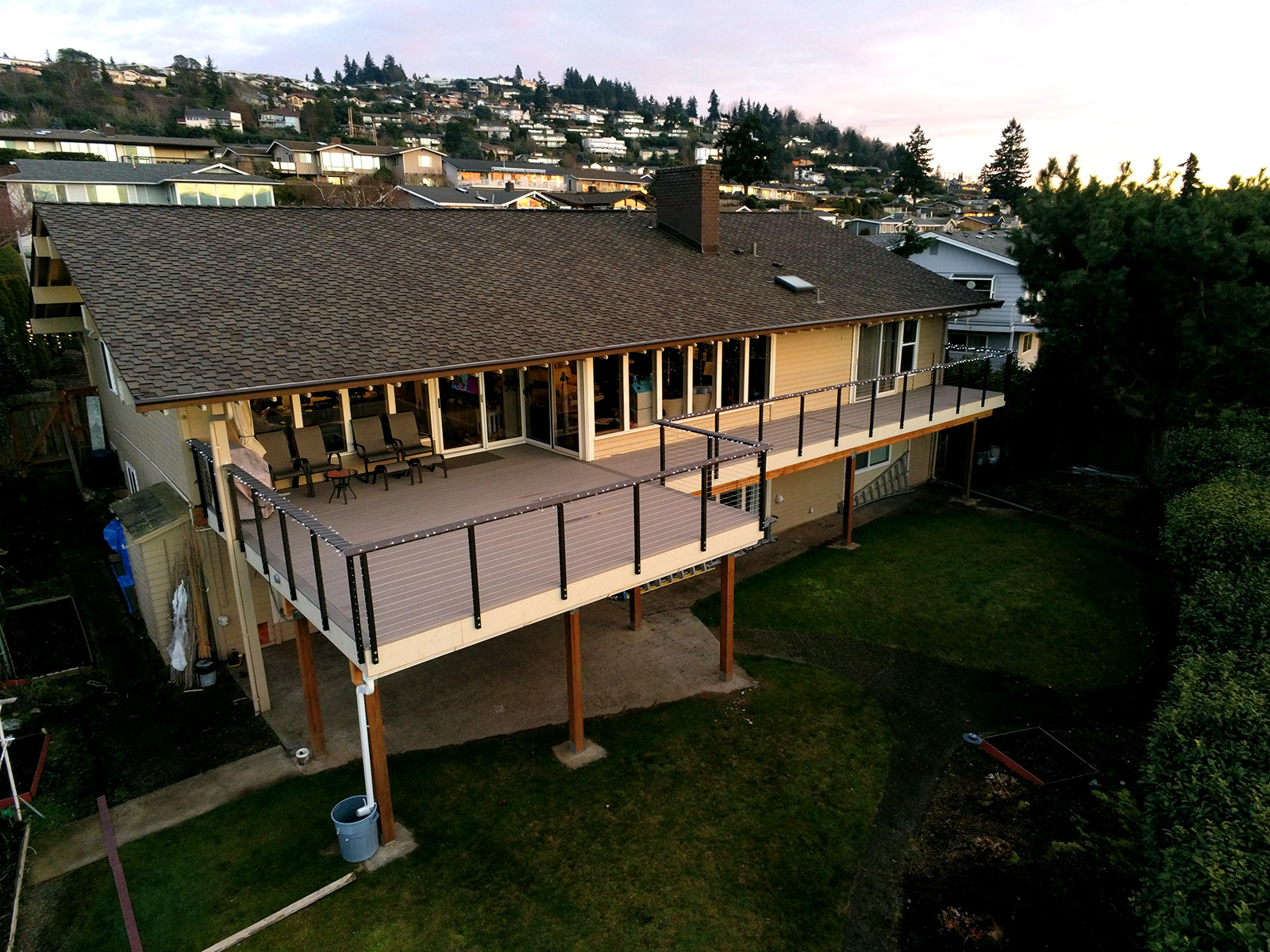 This raised deck balcony mounted in the backyard of the house elevates the homeowner&#8217;s outdoor living space with a view of the city, not obstructed by the custom cable railing.